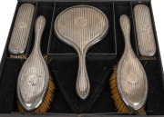 A five piece sterling silver vanity set with mirror and brushes, housed in original fitted box, made in Birmingham, early 20th century, the box 33cm wide.