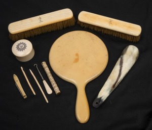 A pair of antique ivory brushes, an ivory circular trinket box, an Italian shoehorn, whalebone pen knife, whalebone needle case (stanhope), whalebone implements and xylonite hand-mirror, 19th and 20th century, (10 items), the shoe horn 19cm long.