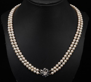 A double strand cultured pearl necklace with white gold, diamond and sapphire clasp, housed in a Hardy Brothers plush box, 55cm long.