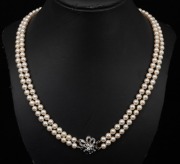 A double strand cultured pearl necklace with white gold, diamond and sapphire clasp, housed in a Hardy Brothers plush box, 55cm long.