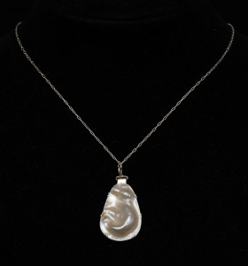 A sterling silver mounted pearl shell pendant on sterling silver chain, housed in a MIKIMOTO branded plush box, ​​​​​​ ​​​​​​​the pendant 3.5cm high, the chain 60cm long.