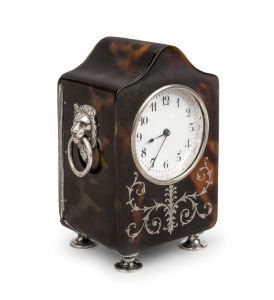 An antique bedside clock in tortoiseshell case with sterling silver plique work front, lion mask handles and feet by William Comyns. French timepiece movement with lever platform escapement, early 20th century, 10cm high.