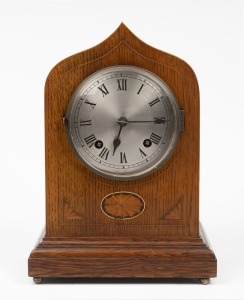 An antique English mantle clock in oak case with marquetry decoration, eight day time and gong strike movement with silvered dial and Roman numerals, early 20th century, 32cm high.
