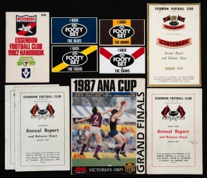 Group comprising Essendon Annual Reports for years 1962 (2), 1965, and 1972, together with Essendon 1982 Handbook, 1987 VFA ANA Cup Grand Finals souvenir magazine, and four unused 1980s TAB "Footy Bet" stickers for Tigers/Hawks/Swans/Blues. (10 items)