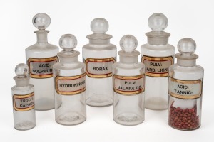 Seven assorted antique glass pharmaceutical glasses of varying sizes, each with original labels, 19th century, the largest 26cm high.