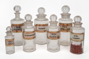 Seven assorted antique glass pharmaceutical glasses of varying sizes, each with original labels, 19th century, the largest 26cm high.