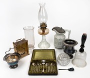 Two pint glass beaker, glass oil lamp, glass bell, silver plated vase and sugar basin with spoon, silver plated teaspoon and tong set, antique stoneware jug with pewter lid, brass quartz clock and lidded crystal bowl, 19th and 20th century, (9 items), the