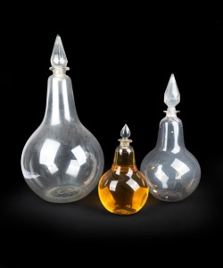 Three graduated antique English glass apothecary carboys, two with ill-fitting facetted glass stoppers, 19th/20th century, A/F, 43cm, 67cm and 88cm high.