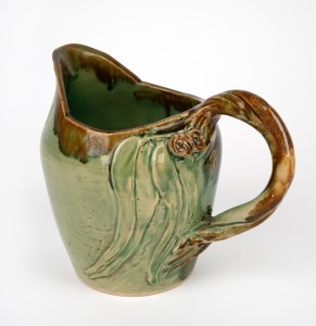 REMUED early green glazed pottery jug with experimental applied gumnuts, leaves and branch handle, incised "Remued, 1933", 18cm high.