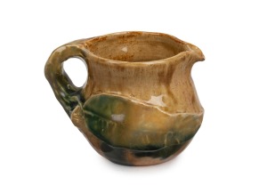 PHILIPPA JAMES green and brown glazed pottery jug with applied gum blossom, branch handle and leaf, incised "Philippa James", 7cm high.