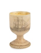 An antique scrimshaw whales tooth egg cup, adorned with whaling scenes and tallships, engraved "GEO. TYSON. 1859", 7cm high. - 2