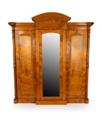 An antique Australian huon pine three door breakfront wardrobe with bevelled mirror plate central door, arched pediment and full-length carved and fluted columns, circa 1870, ​​​​​​​234cm high, 220cm wide, 73cm deep.