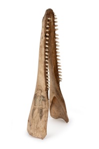 A scrimshaw dolphin jawbone adorned with female portrait in "flapper" art deco costume, circa 1930s, 37cm long.
