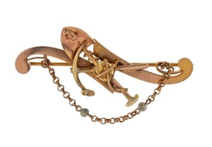 An antique 18ct gold miner's brooch with crossed pick and shovel, gold nugget specimens, entwined rope and seed pearl, 19th century, housed in a period box branded "ISAAC ABRAHAM, 211-213 Mair St, BALLARAT", stamped "18ct", 5.1cm wide, 5.1 grams.