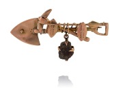 A South African 9ct gold miner's brooch with cross pick and shovel plus mineral specimen and rare Zulu shield and spear decoration, 19th century, stamped "9ct", ​​​​​​​4.7cm wide, 3.5 grams total.