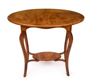 A handsome antique New Zealand totara occasional table with well figured two piece oval top, slender cabriole scroll legs and lower tiered shelf, circa 1910, the underside with maker's ink stamp (illegible), 73cm high, 81cm wide, 48cm deep.