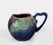 REMUED blue glazed pottery jug with applied gumnuts and leaves, incised "Remued, Hand Made, 1934", 12cm high.