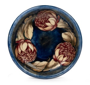 MOORCROFT "Waratah" pottery bowl on blue ground with a flambe blush, impressed signature mark to base "Moorcroft, Potters To H.M. The Queen,. Made In England", 26.5cm diameter.