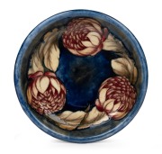 MOORCROFT "Waratah" pottery bowl on blue ground with a flambe blush, impressed signature mark to base "Moorcroft, Potters To H.M. The Queen,. Made In England", 26.5cm diameter.