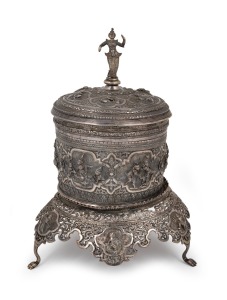 36 · An antique Burmese silver cylindrical lidded box on stand with repousse decoration and finely cast figural finial, early 20th century, 31cm high, 1425 grams.