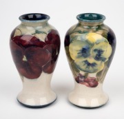 MOORCROFT "Pansy" pair of miniature pottery vases on cream ground, one with green interior, the other in blue, impressed factory marks and signatures to the bases, ​​​​​​​10.5cm high. - 2