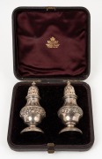 A pair of sterling silver pepper pots, made in London, circa 1885stamped "JSB", in original plush lined presentation box for Skinner of Orchard Street, London, 9cm high, 87 grams.