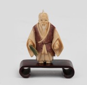 A Japanese carved ivory netsuke with hand-painted finish, on timber stand, 20th century, ​​​​​​​6cm high overall.