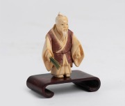 A Japanese carved ivory netsuke with hand-painted finish, on timber stand, 20th century, ​​​​​​​6cm high overall. - 2