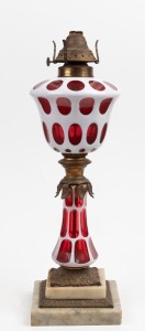 An antique oil lamp with ruby overlay glass font and base with gilt metal and marble mounts, mid 19th century, ​​​​​​​49cm high.
