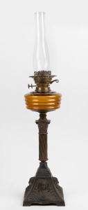 An antique oil lamp with amber glass font, double burner, gilt metal column and base with glass chimney, (later shade, damaged), 19th century, 76cm high.