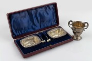 A pair of English sterling silver salt cellars with spoons housed in original fitted case, together with a miniature sterling silver trophy cup, 20th century, the cup 7cm high, 60 grams total.