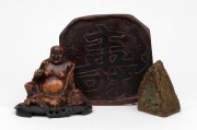 A Chinese carved soapstone Buddha statue affixed to wooden stand; together with a Chinese jadeite stone carving and a carved wooden stand, 20th century, (3 items), the largest 11cm high.