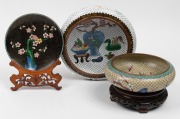 A Chinese cloisonne plate on carved timber stand, together two Chinese cloisonne bowls, one on carved stand, 20th century, (3 items), the largest 25cm diameter.