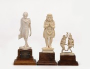 Three Indian carved ivory figures on timber stands, including Mahatma Gandhi, 20th century, the largest 11cm high overall.