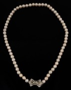 A vintage cultured pearl necklace fastened by an impressive 14ct white gold and diamond clasp, mid 20th century, 62cm long, the clasp 3cm wide.