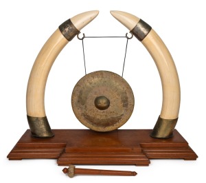 170 · An impressive dinner gong, crafted from ivory tusks mounted in gilt metal, resting on a teak base, early to mid 20th century, an imposing 70cm high, 93cm wide, 31cm deep.