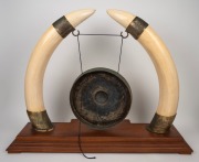 An impressive dinner gong, crafted from ivory tusks mounted in gilt metal, resting on a teak base, early to mid 20th century, an imposing 70cm high, 93cm wide, 31cm deep. - 2