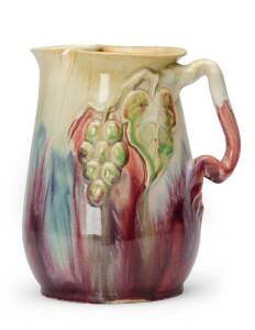 REMUED: Pottery jug with applied branch handle, grapes & leaf glazed in pink, green & cream. 19.5cm