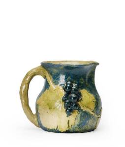 MERRIC BOYD: Pottery jug with applied grapes & leaves glazed in blue & gray with incised landscape scene, signed & dated 1942. PROVENANCE: Hurnall Colletion, Joels Auctions. 18.5cm