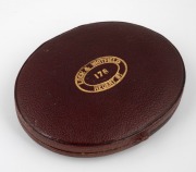An antique English oval miniature portrait of a lady in blue and white, hand-painted on ivory, housed in original scarlet leather and silk lined case with embossed retailer's details "LOCK & WHITFIELD 178 REGENT ST.", 19th century, 9.5cm high overall - 2