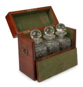 An antique mahogany cased campaign tantalus, housing three hobnail cut crystal decanters, 19th century, 26cm high, 30cm wide, 13cm deep.