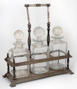 An antique silver plated tantalus with swing handle, housing three assorted decanters, 19th/20th century, 36cm high handle up.
