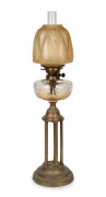 An antique banquet lamp with clear cut crystal font, black button double burner, acid etched peach shade and brass column bird cage base, 19th century, 77cm high overall.
