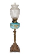 A banquet lamp, blue glass font with gilt and floral enamel highlights, black button double burner with acid etched shade and Corinthian column base, 19th century and later, 79cm high.