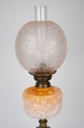 An oil lamp with floral peach glass font, acid etched floral shade, single black button burner and unusual cast metal Chinese acrobat base, 19th century and later, 70cm high. - 2
