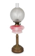 An antique oil lamp with square form pink glass font, double burner, acid etched glass shade and brass column base, 19th/20th century, ​​​​​​​67cm high.