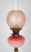 An antique oil lamp with pink glass font, white button double burner, pink acid etched shade and brass column base, 19th/20th century, 71cm high. - 2
