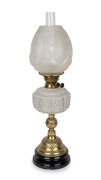 An antique oil lamp with milk glass font, black button burner, acid etched shade and glass chimney, mounted on an ornate black ceramic and brass base, 19th/20th century, 65cm high.