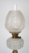 An antique oil lamp with milk glass font, black button burner, acid etched shade and glass chimney, mounted on an ornate black ceramic and brass base, 19th/20th century, 65cm high. - 2