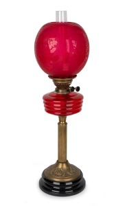 Antique style oil lamp with ruby glass font and shade, black button burner on brass column and black ceramic base, 20th century, 67cm high.